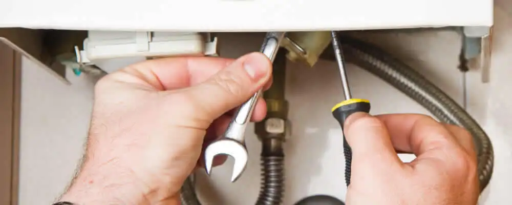 Boiler repair technician tightening pipe fittings and connections in Pasadena, CA