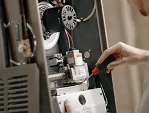 Furnace repair technician inspecting internal components and wiring in Pasadena, CA