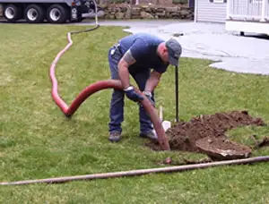 Septic pumping technician servicing a residential septic tank with a vacuum hose in Pasadena, CA