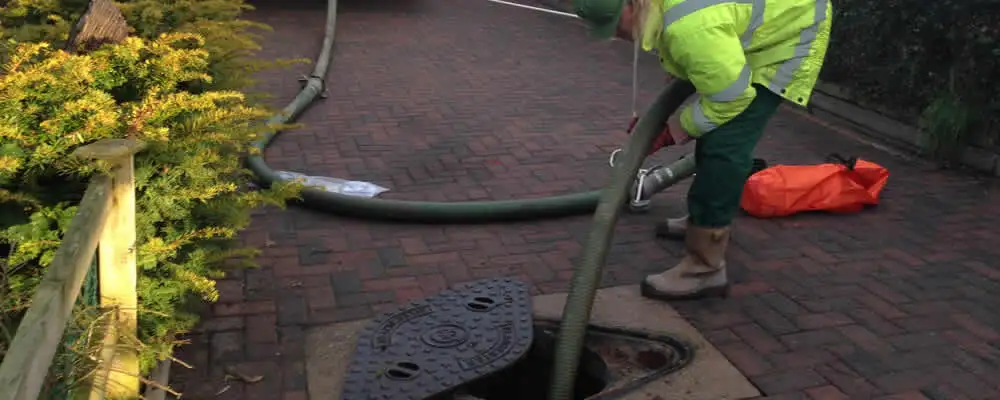 Septic tank cleaning technician servicing a septic tank with a vacuum hose in Pasadena, CA