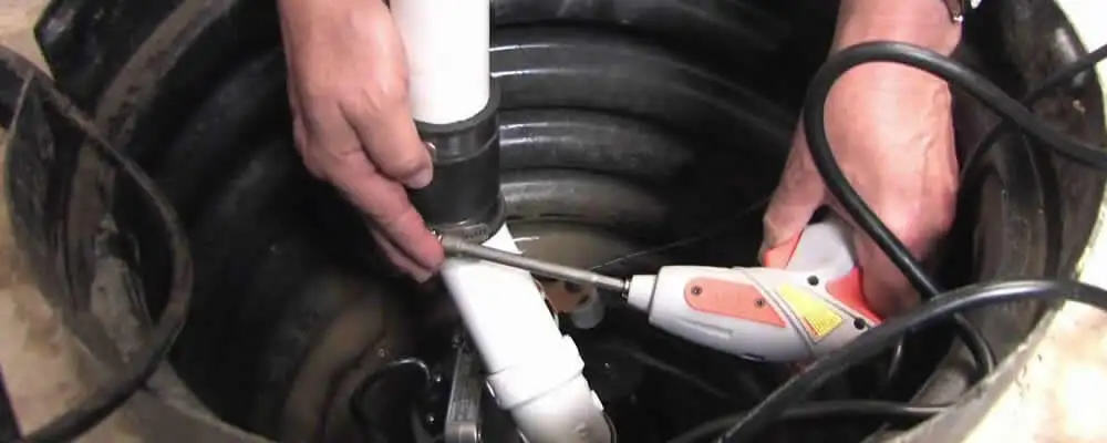 Sump pump installation technician connecting PVC discharge piping in Pasadena, CA