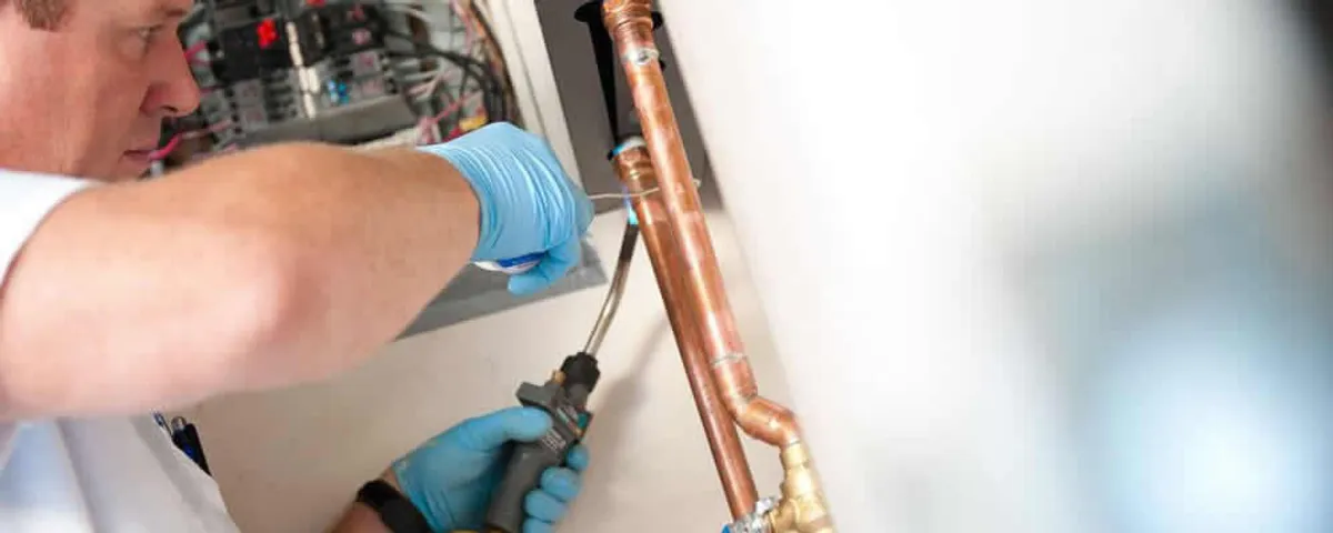 Water heater repair technician testing copper pipe connections and controls in Pasadena, CA
